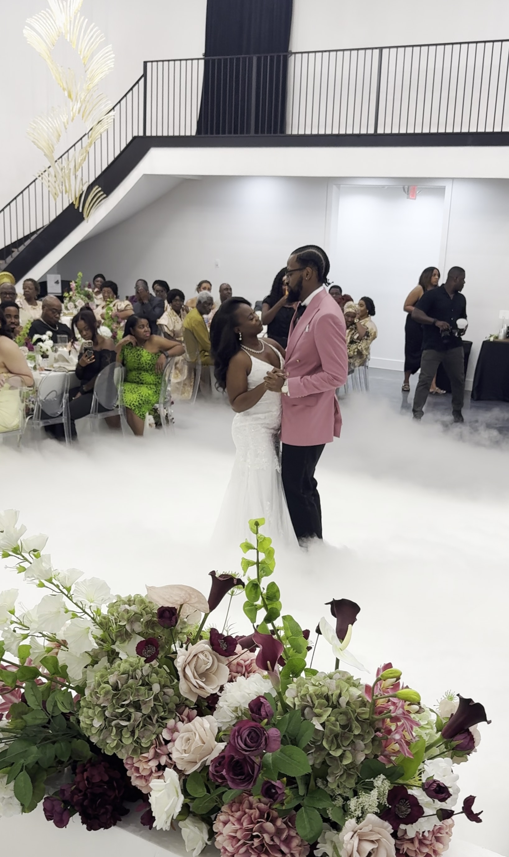 Newlyweds sharing their first dance surrounded by low clouds and wedding guests
